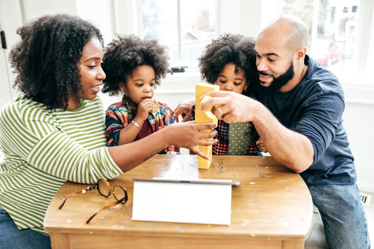 Parents and young children playing and learning together at a table, symbolizing MindWay ABA’s parent training program in Carmel that empowers families with tools and strategies to support their child’s growth through everyday moments.
