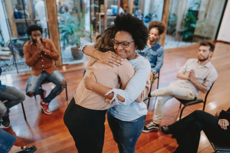 Two people embracing warmly in a supportive group setting, symbolizing the compassion, connection, and understanding shared through MindWay ABA’s parent support groups in Carmel, Indiana.