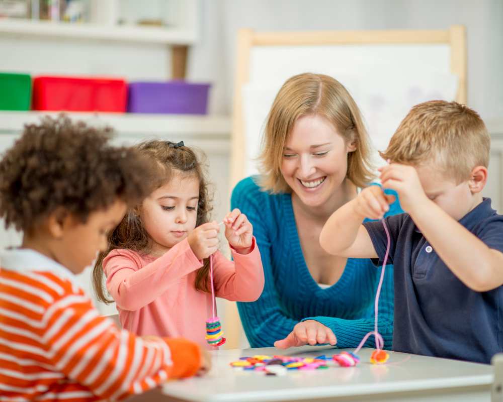 Children working together with a teacher in a calm Montessori classroom, engaging in hands-on activities that support focus, fine motor skills, and inclusive learning.